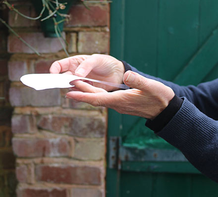  A close-up of hands gently holding a white paper object that makes itself ghostly to the camera through its trembling movement.